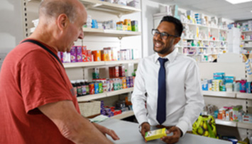 Male pharmacist talking to customer over counter
